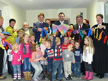 Im Beisein der Kinder wurde mit dem Durchschneiden eines bunt geschmückten Bandes die neue Rugendorfer Kinderkrippe freigegeben. Unser Bild zeigt umrahmt von den Kleinen der Gemeinde Rugendorf (von links) Leiterin Waltraud Bauer, MdL Inge Aures, Architekt Hans Spindler, Bürgermeister Martin Weiß, stellvertretender VG-Vorsitzenden Bernd Kotschenreuther (verdeckt), MdL Martin Schöffel, Landrat Klaus Peter Söllner und Pfarrerin Kathrin Klinger. Foto: Klaus-Peter Wulf