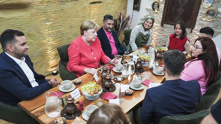 In einem syrischen Restaurant in Berlin spricht Angela Merkel mit Menschen, die einst nach Deutschland flüchteten.