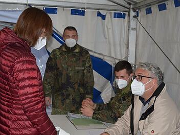 Vor dem Eingang zum Impfzentrum Tattersall melden sich Personen, die sich impfen lassen wollen, beim Empfangsteam im Zelt an. Im Bild rechts zwei Soldaten der Bundeswehr und ein Helfer der Carl-von-Heß-Stiftung Hammelburg.