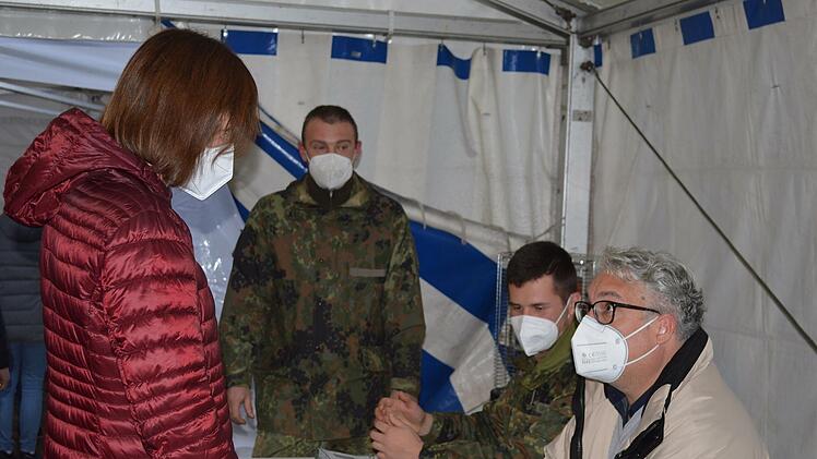 Vor dem Eingang zum Impfzentrum Tattersall melden sich Personen, die sich impfen lassen wollen, beim Empfangsteam im Zelt an. Im Bild rechts zwei Soldaten der Bundeswehr und ein Helfer der Carl-von-Heß-Stiftung Hammelburg.