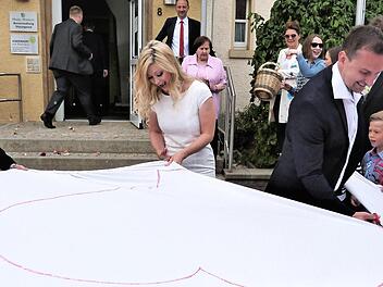 Unser Bild zeigt das Brautpaar beim Ausschneiden eines Herzens, das die Mitarbeiter der Zahnarztpraxis vorbereitet hatten. Foto: Werner Reißaus