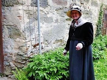 Hedda Hanft als Therese Schmidt im Empire-Barockkleid kontrolliert während der Kostümführung auch das Wachstum im Garten.  Fotos: Volker Gundel