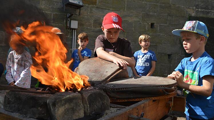 Die Forchheimer Schüler Jan und Felix pumpen am Blasebalg, damit die Glut heiß wird. Im Burggraben der Kaiserpfalz werden Nägel geschmiedet.  Foto: Ronald Heck