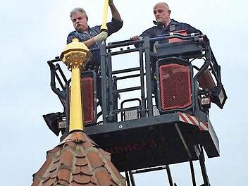 Restaurator Erwin Bickel setzt das Turmkreuz auf. Foto: Manfred Welker