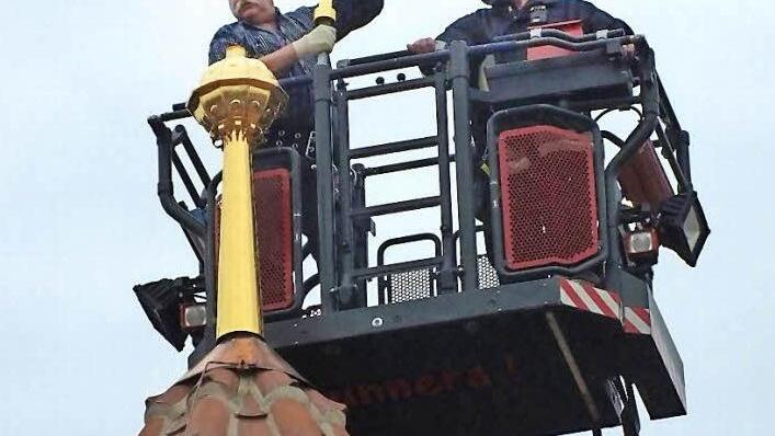 Restaurator Erwin Bickel setzt das Turmkreuz auf. Foto: Manfred Welker