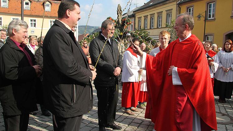 Andächtig stehen die Erwachsenen auf dem Marktplatz und lassen ihre Palmzweige von Dekan Hans Roppelt segnen.