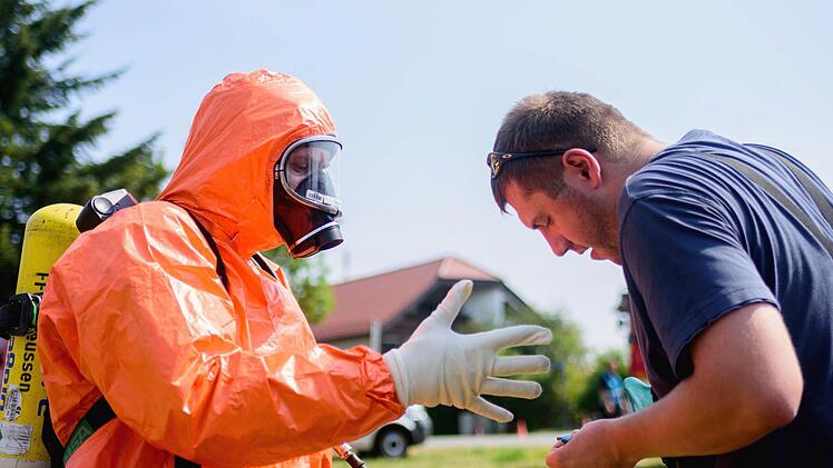 Einsatzkräfte der Feuerwehr mit Ganzkörper-Schutzanzügen sitzen am 11.08.2015 in Engelmannsreuth (Bayern) in einem Einsatzfahrzeug. Bei Engelmannsreuth ist ein F-16 Kampfjet der US-Streitkräfte abgestürzt. Foto: Nicolas Armer/dpa