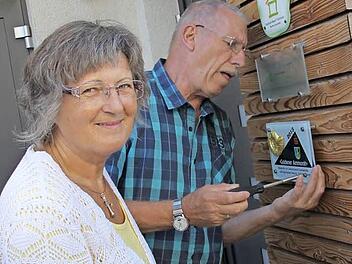 Rita Wittmann hat durch den Umzug in die Sentinel-Wohnung gesundheitlich profitiert. Sie und ihr Mann Horst, der hier gerade die Plakette des Baupreises "Goldener Ammonit" anschraubt, sind eine von drei Eigentümerparteien im Haus. Fotos: Ramona Popp
