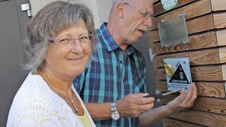 Rita Wittmann hat durch den Umzug in die Sentinel-Wohnung gesundheitlich profitiert. Sie und ihr Mann Horst, der hier gerade die Plakette des Baupreises "Goldener Ammonit" anschraubt, sind eine von drei Eigentümerparteien im Haus. Fotos: Ramona Popp