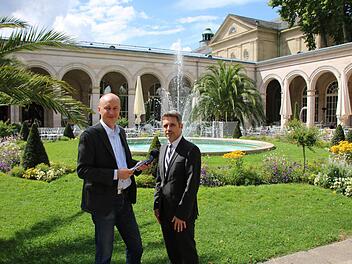 Interview-Termin in malerischer Atmosphäre: Redakteur Ralf Ruppert (von links) traf sich mit Kurdirektor Frank Oette im Kurgarten, im Hintergrund ein Teil des Arkedenbaus und der Regentenbau. Foto: Sebastian Elsässer