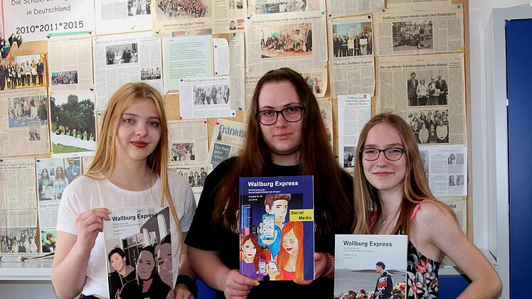 Voller Stolz zeigen die Schülerinnen Christina, Emilia und Sophie (von links) die letzten Ausgaben des "Wallburg-Express" vor ihrer großen Pressewand.