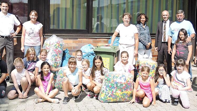 Die Marktleugaster Schüler mit ihren gesammelten Deckeln und (stehend von links) dem Initiator der Aktion und Elternbeiratsvorsitzendem Marc Hartenberger, den Elternbeiräten Kerstin Pittroff, Anja Vogel, der stellvertretenden Schulleiterin Annette Marx, 1. Bürgermeister Franz Uome, Roland Rödel vom Getränkehandel Rödel aus Marktleugast mit Enkeltochter Robin sowie Michaela und Johannes Döring. Foto: Klaus-Peter Wulf