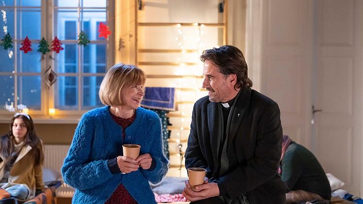 Oliver Mommsen ging zur Vorbereitung auf seine Rolle als Priester, der hier mit Ursela Monn einen Plausch h&auml;lt, auch in die Kirche. Privat findet er Weihnachten "bekloppt".