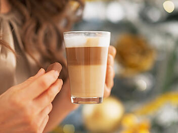 Nahaufnahme einer jungen Frau mit S&uuml;&szlig;igkeiten und einem Latte Macchiato  Closeup on young woman with candy and latte macchiato
