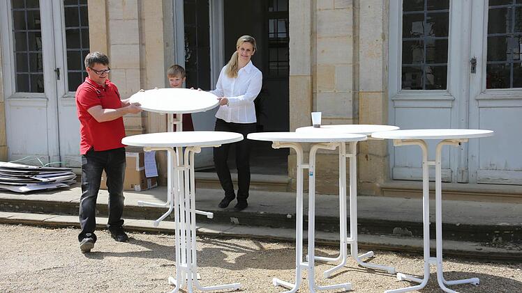 Karin und Jörn Weinert tragen mit Hilfe von Sohn Dennis ein paar Stehtische vor den Rosengarten-Pavillon. Foto: Matthias Hoch