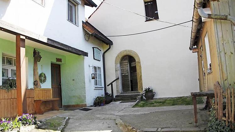Zwischen beiden Türen hängt die Tafel an der Wand am oberen Eingang der Klaussteinkapelle. Man muss dazu um den Bauernhof herumgehen, der hier mit der Kirche verschmilzt. Foto: Reinhard Löwisch