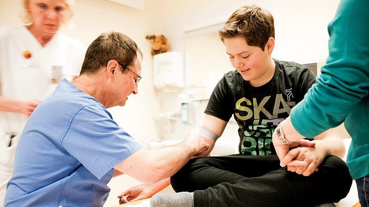 Auch bei seiner 250. Transfusion sticht ihn sein Arzt Dr. Glöckel. Seine Mutter hält ihm noch immer die Hand dabei. Foto: Lea Schreiber