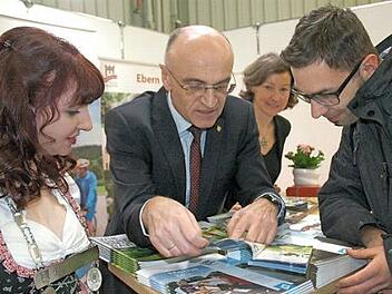 Landrat Wilhelm Schneider, die Gesch&auml;ftsf&uuml;hrerin des Ha&szlig;berge-Tourismus, Susanne Volkheimer, und die Bierprinzessin Kerstin Friedrich (links) machen auf der Freizeitmesse kr&auml;ftig Werbung f&uuml;r Urlaub in den Ha&szlig;bergen. Oliver Milisch (rechts) aus Mainleus interessierte sich vor allem f&uuml;r Radtouren durch die Region.  Foto: Moni G&ouml;hr/Landratsamt Ha&szlig;berge