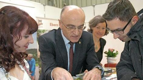 Landrat Wilhelm Schneider, die Gesch&auml;ftsf&uuml;hrerin des Ha&szlig;berge-Tourismus, Susanne Volkheimer, und die Bierprinzessin Kerstin Friedrich (links) machen auf der Freizeitmesse kr&auml;ftig Werbung f&uuml;r Urlaub in den Ha&szlig;bergen. Oliver Milisch (rechts) aus Mainleus interessierte sich vor allem f&uuml;r Radtouren durch die Region.  Foto: Moni G&ouml;hr/Landratsamt Ha&szlig;berge