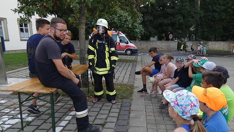 Zweiter Vorsitzender Christian Vogt (links) erkl&auml;rte den Kindern die Ausr&uuml;stung eines Atemschutztr&auml;gers, die der Jugendfeuerwehrler Kilian Nowak vorf&uuml;hrte. Foto: Christian Licha