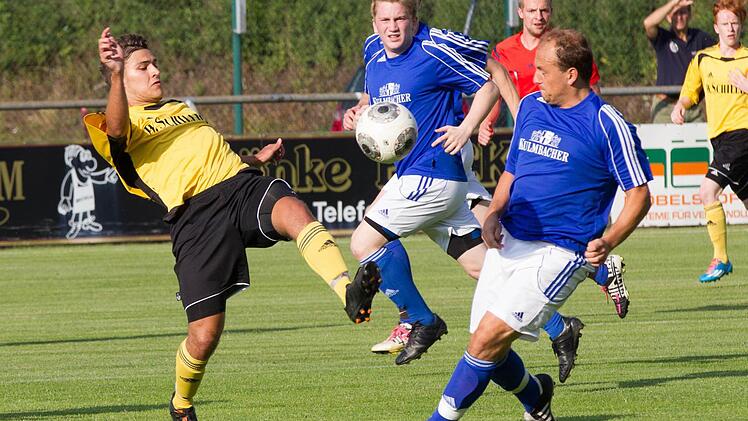 Im Mittelfeld versucht der Frohnlacher Jannik Schmidt (gelb) mit einem langen Bein noch vor Jochen Hollfelder an die Kugel zu kommen. In der Mitte Daniel Weiner.