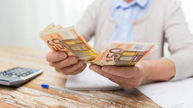 Mann h&auml;lt Geld in der Hand.