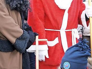 Vermummte auf dem Ebensfelder Weihnachtsmarkt? Dass Nikolaus und sein Knecht Rupprecht nahezu ganzk&ouml;rperverschleiert sind, war wohl eher den Minusgraden als einem religi&ouml;sen Statement geschuldet. Der kleine Junge griff trotzdem beherzt zu. Foto: Mario Deller
