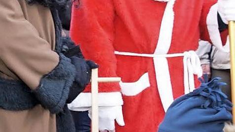 Vermummte auf dem Ebensfelder Weihnachtsmarkt? Dass Nikolaus und sein Knecht Rupprecht nahezu ganzk&ouml;rperverschleiert sind, war wohl eher den Minusgraden als einem religi&ouml;sen Statement geschuldet. Der kleine Junge griff trotzdem beherzt zu. Foto: Mario Deller