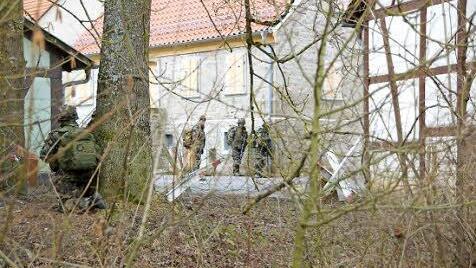 Ein Soldat kauert an einem Baum.