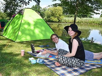 Decke, Kreuzworträtselheft und Handy-Lautsprecher: Timo Schlesinger und Lara Kröger haben ihr Camping-Wohnzimmer am Regnitzufer aufgebaut. Foto: Ronald Rinklef