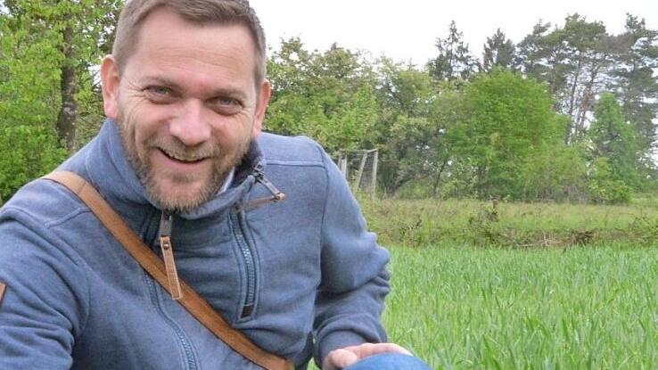 Alexander Ulmer vom LBV zeigt rote Adonisröschen am Rand eines Ackers am Lauterberg. Daneben die Blüten in Großaufnahme, bei Sonnenschein geöffnet. Fotos: Rainer Lutz/Alexander Ulmer