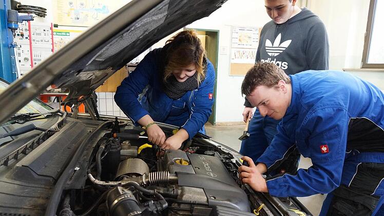 Sophie Mettendorf, Jonas Brosig und Stephan Günther schrauben am Motorraum eines Autos.Foto: Arkadius Guzy