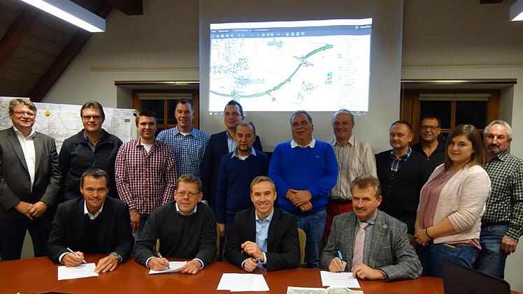 Unterzeichnung der Petition (von links): vorne: Georg Hemmerlein, Matthias Rothe, Bernd Höfer und Ludwig Weiß unterschreiben die Stellungnahme der Gemeinde Meeder im Beisein (dahinter stehend) von Gemeinderäten und weiteren Gästen. Foto: Lothar Weidner