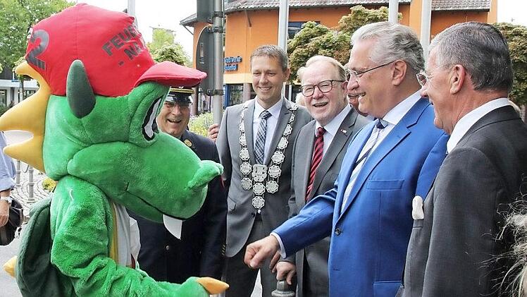 Handschlag mit Löschdrache: Innenminister Joachim Herrmann (Zweiter von rechts) sowie die Ehrengäste wurden von "Löschi", dem bei den Landkreisfeuerwehren entwickelten Maskottchen der Jugendfeuerwehren, empfangen. Fotos: Michael Stelzner