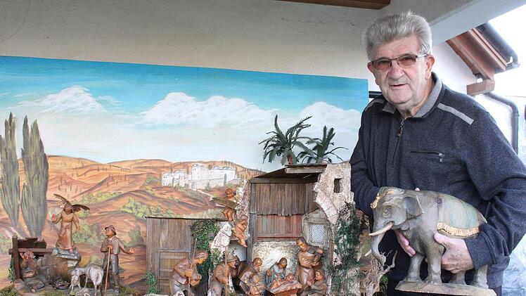 Der Elefant ist eine prächtige Holzfigur, die zu dieser von Florian Hofmann überarbeiteten und mit passendem Hintergrundbild versehenen Krippe gehört. Die Darstellung der Geburt Jesu ist ein Teil mehrerer biblischer Szenen, die alle in der Krippenschau hätten gezeigt werden sollen.