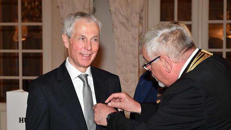 Oberbürgermeister Norbert Tessmer (links) heftet dem scheidenden Sprecher der HUK-Vorstände, Wolfgang Weiler, die Bürgermedaille an. Foto: Ronald Rinklef