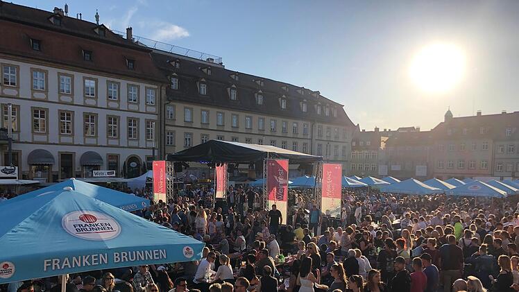 Menschenmenge auf dem Bamberger Weinfest bei Sonnenschein. Viele Besucher genießen die festliche Atmosphäre und die Angebote an den Ständen unter blauen Zelten im historischen Stadtkern.