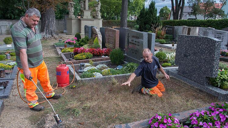 Die Mitarbeiter des Bauhofes, im Bild (von links) Wladimir Mueller und Jens Neugebauer), sind derzeit dabei, aufgelassene Gräber und Wege im Friedhof in Wonfurt mit dem Gasbrenner vom Unkraut zu befreien. Bürger hatten sich über den Zustand beschwert, sind aber selbst nicht bereit, bei der Pflege des Friedhofs mitzuarbeiten.
