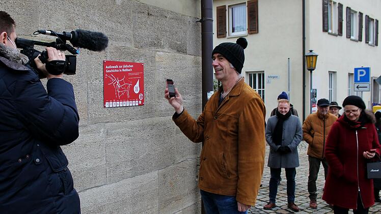 Ingo Pfeiffer scannt den QR-Code des Audiowalk am Rathaus Maßbach, gefilmt vom Reporter des BR im Hintergrund Bürgermeister Matthias Klement und Theaterleiterin Anne Maar.    Fotos: Werner Vogel