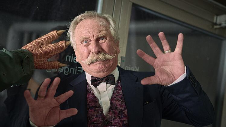 Schuldirektor Udo Brückmann (Henning Krautmacher) muss mit einem Dinosaurier kämpfen.