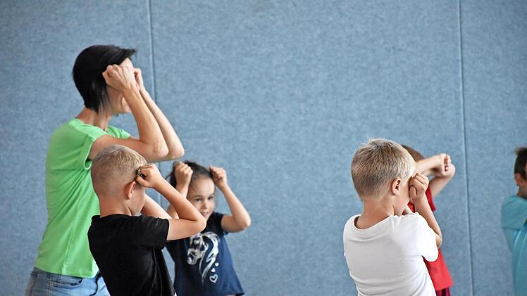Hier zeigt ein Übungsleiter den Kindern, wie sie ihren Kopf schützen können.