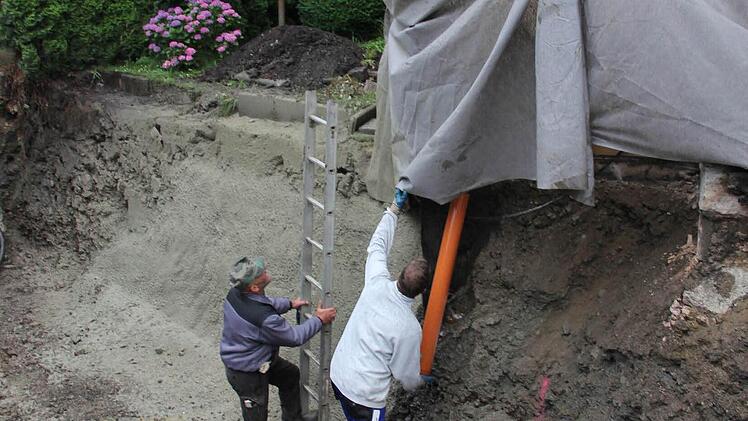 Der Wassereintritt von einer Dachrinne in die Baustellengrube macht den Arbeitern zu schaffen.  Foto: Friedwald Schedel