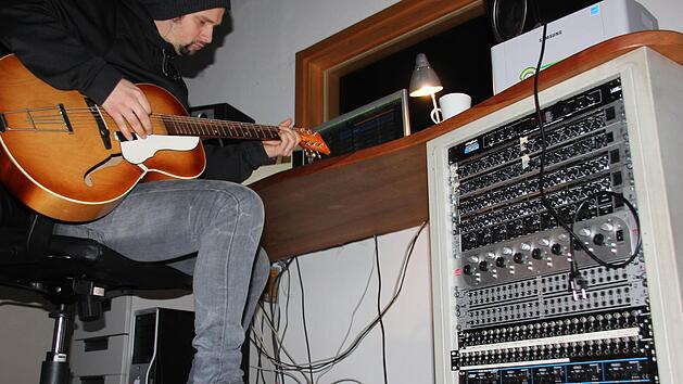 Johannes Dorsch mit Gitarre am Mischpult im Regieraum seines Tonstudios in Ebern. Fotos: Ralf Kestel