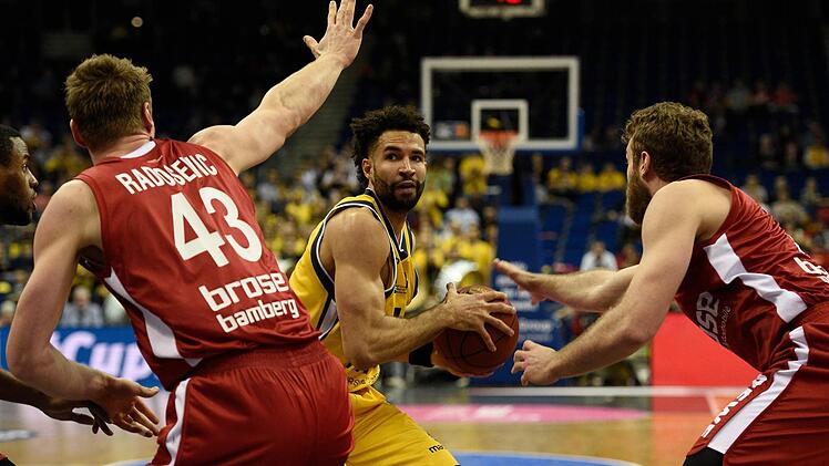 Leon Radosevic (l.) und Nicolo Melli (r.) stoppen Drew Crawford. Foto: dpa