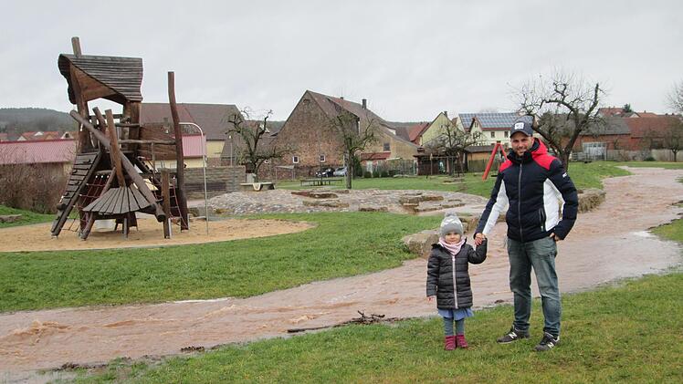 Nichts wird es mit dem Spielen am Mehrgenerationen-Platz für die kleine Matilda. Der randvolle Deisselbach verhinderte ihr und Papa Matthias den Zugang. Foto: Winfried Ehling