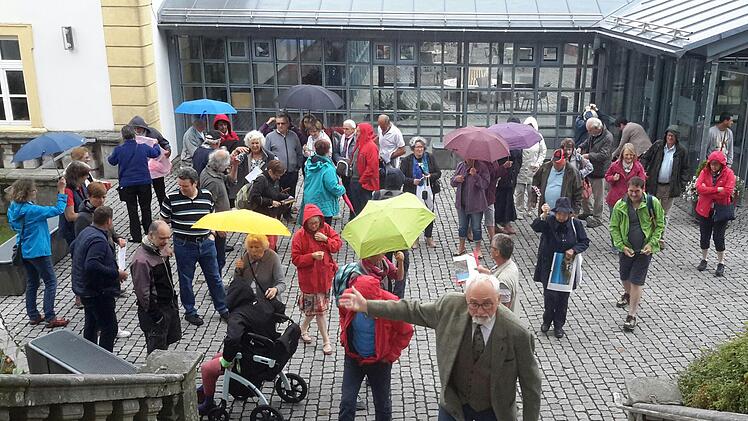 Ein stabiler Schirm und praktische Regenbekleidung taten beim Abstecher auf den Volkersberg gute Dienste. Gastgeber Wilfried Beck (vorn im Bild) führte die Besucher aber schnell ins Trockene.Foto: Rolf Pralle