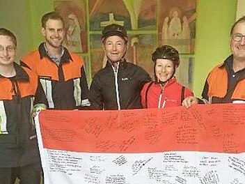 Die Feuerwehrleute David Pfeufer, Anton und Dieter Gerstenkorn (von links) zeigen mit Yvonne Brokop und Olaf Vicktor die Fahne, auf der sich die Feuerwehr mit guten Wünschen verewigt hat. Foto: Katharina Becht