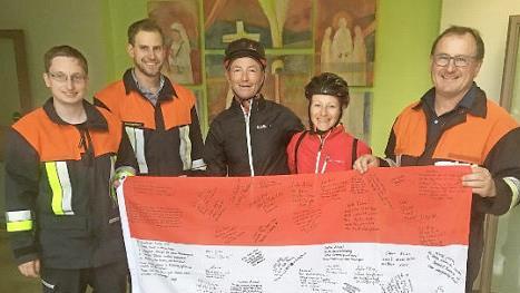 Die Feuerwehrleute David Pfeufer, Anton und Dieter Gerstenkorn (von links) zeigen mit Yvonne Brokop und Olaf Vicktor die Fahne, auf der sich die Feuerwehr mit guten Wünschen verewigt hat. Foto: Katharina Becht