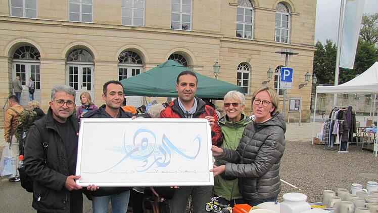 Ist das ein ein kunstvoll geschriebener Koranvers. Mohammed R., Nima S.  und Sasan A. wissen es auch nicht genau. Ein schöner Wandschmuck ist es  allemal. Verkäuferinnen sind Antje Hennig und Mutter Hiltrud.