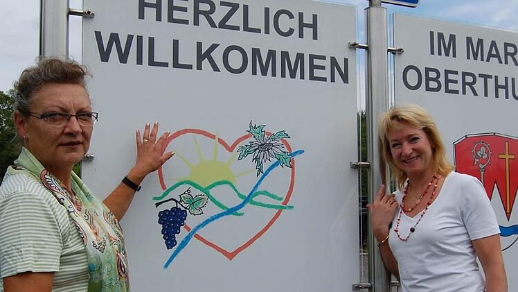 Birgitt Blum (links) und Silvia Friedrich erklären das Logo des Vereins "Tourismus Thulbatal". Foto: Günther Straub